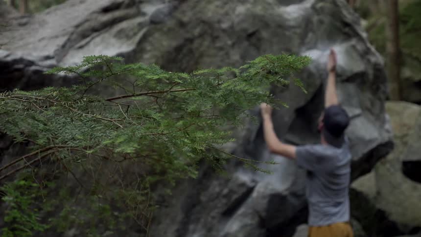 A man reaches for a good hand hold on a rock