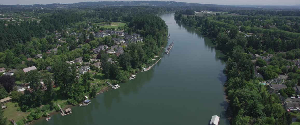 An aerial shot of a small town by the highway with a bridge over a river