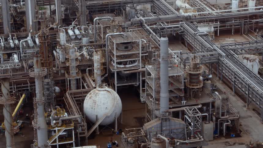 An aerial view of an old industrial site with rusted tanks and smoke stacks