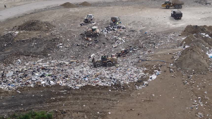 A landfill with tractors and trucks on the property driving around