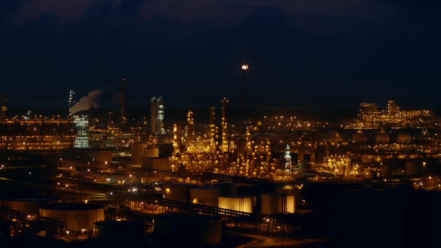 Aerial few of a refinery chimney lit up by flames at blue hour
