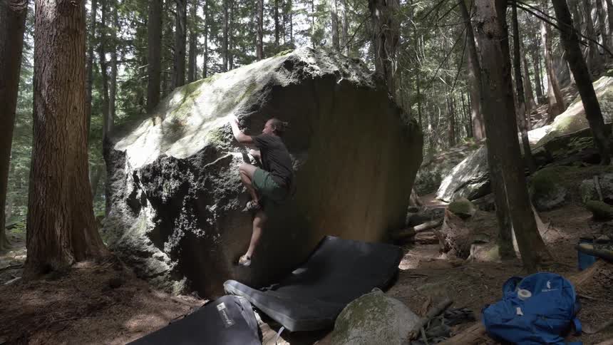 Woman climbs a large boulder in the woods