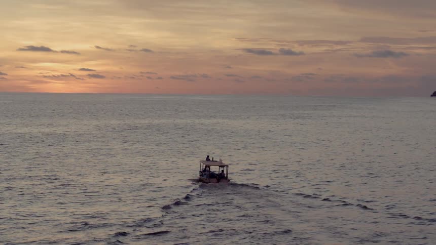 A speedboat rips through the ocean at dusk