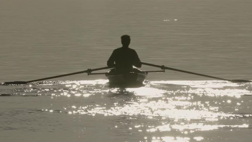 A person rows a boat through the water
