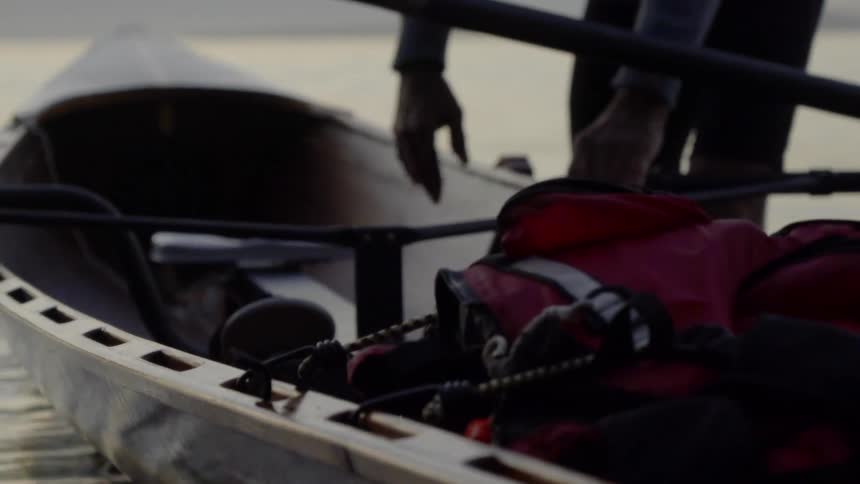 Man reaches across rocking canoe