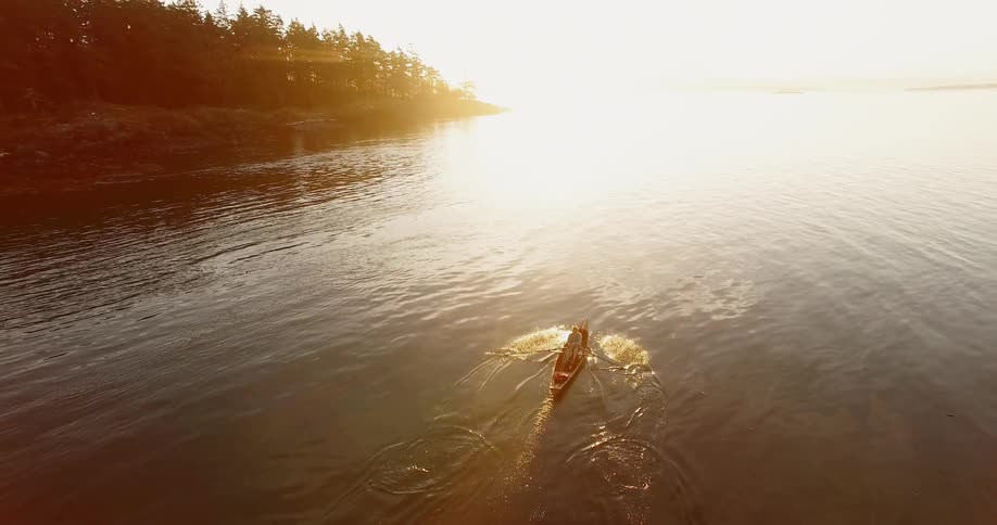 A person rows a boat across a lake