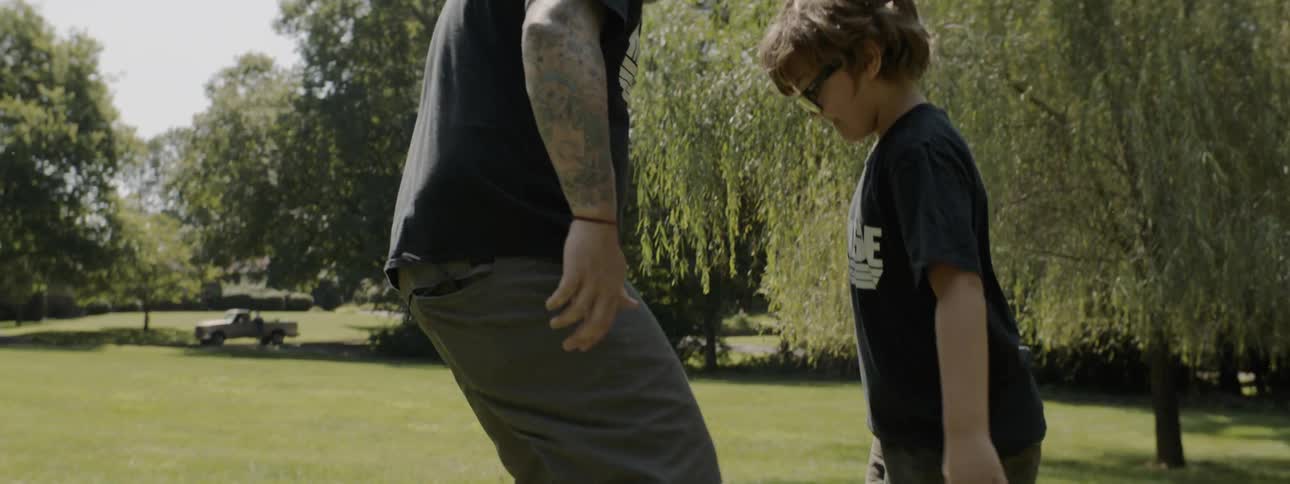 A male caucasian playing soccer with a young male in a field