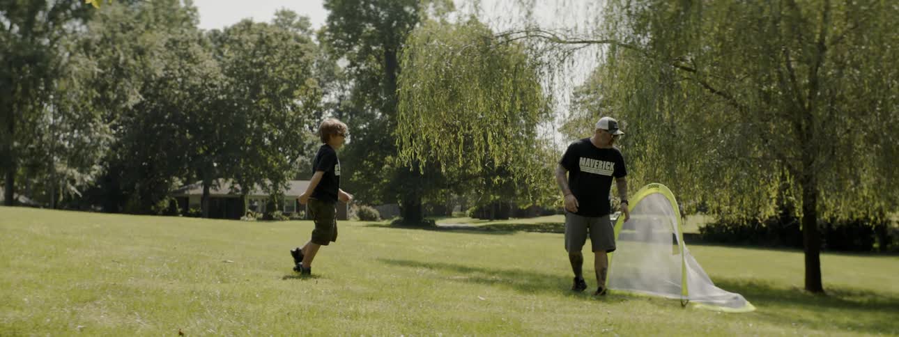 A father and son are playing soccer outdoors