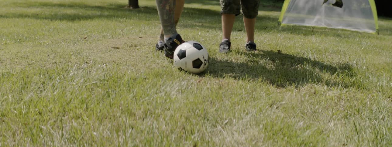A young boy and a man playing soccer on the grass