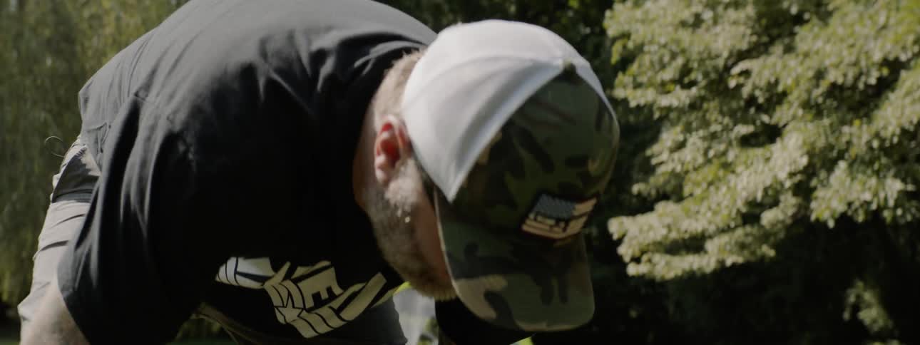 Man wearing cap has fun with child on the field of grass in public park during daylight