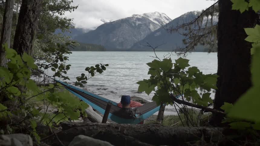 A man swings in a hammock on the shoreline