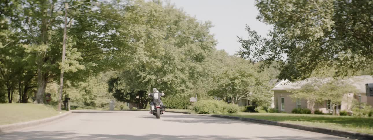 A man on a motorcycle rides through a suburb