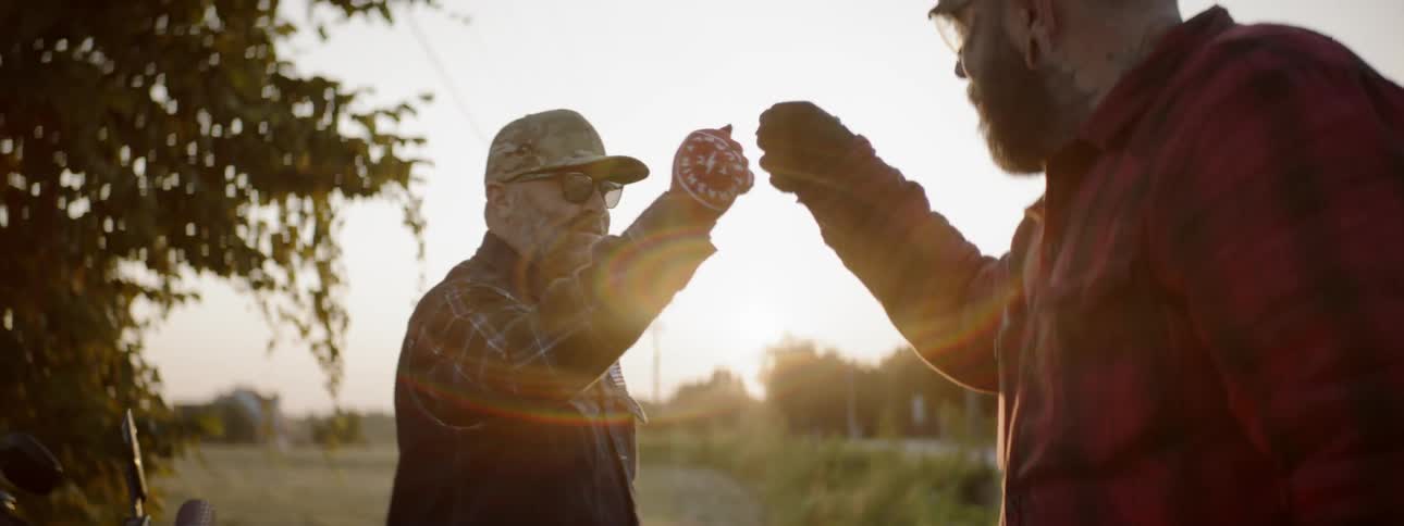 Two men bump fists next to a road