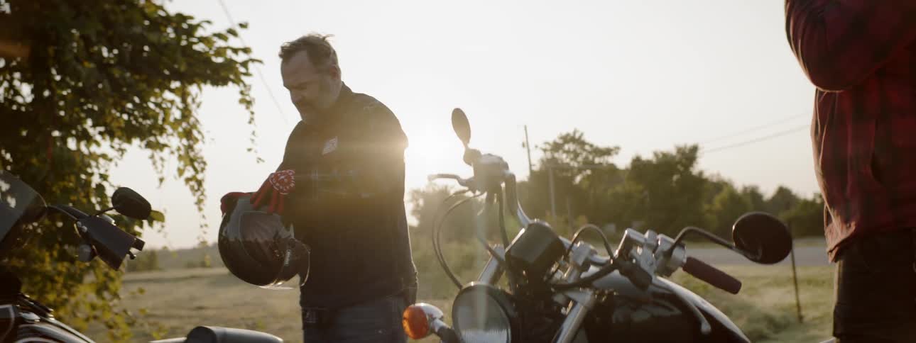 A man is fixing the straps of his motorcycle helmet