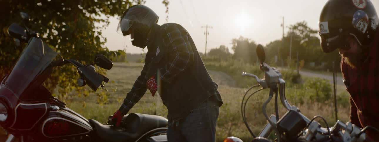 Two motorcyclists get ready to ride again in a rural area