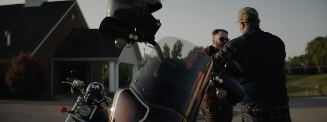 Two men fist bump one another after getting off their motorcycles