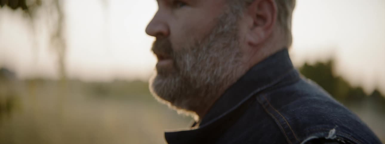Bearded man wears cap outdoors at sunset