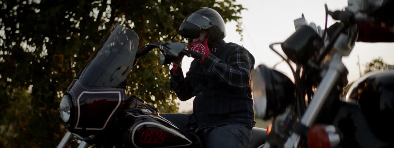 Two motorcyclists sit on their bikes then get off