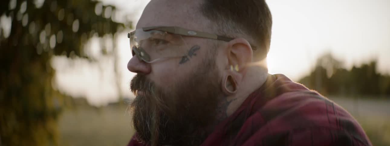 A man wearing safety glasses sits down under a sunset