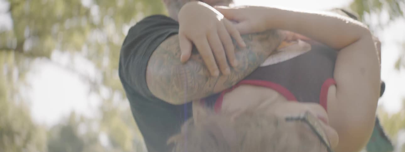 Man holds hand of boy and lifts him up outdoors on a sunny day