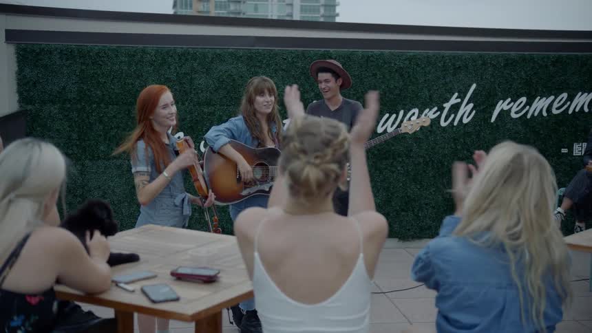 A band of a guitarist bassist and violinist finish a song and receive the applause of a crowd