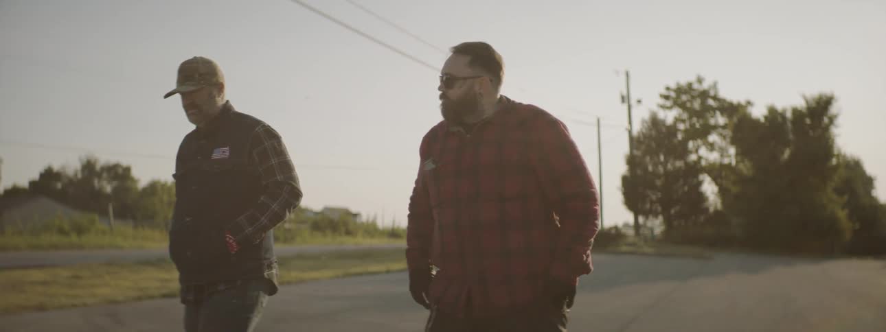 Two men walk across parking lot away from building toward motorcycles