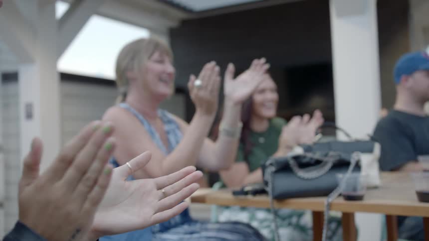 A group of white people sit outdoors and applaud