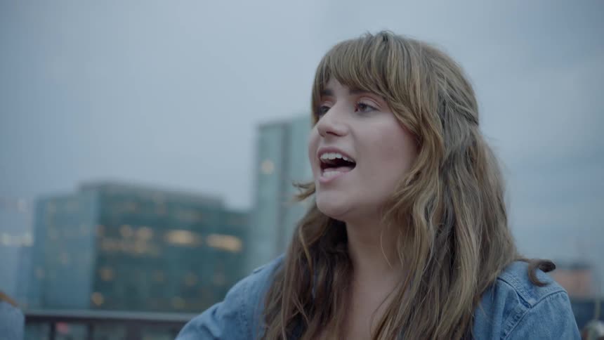 Two women play instruments and sing in a city