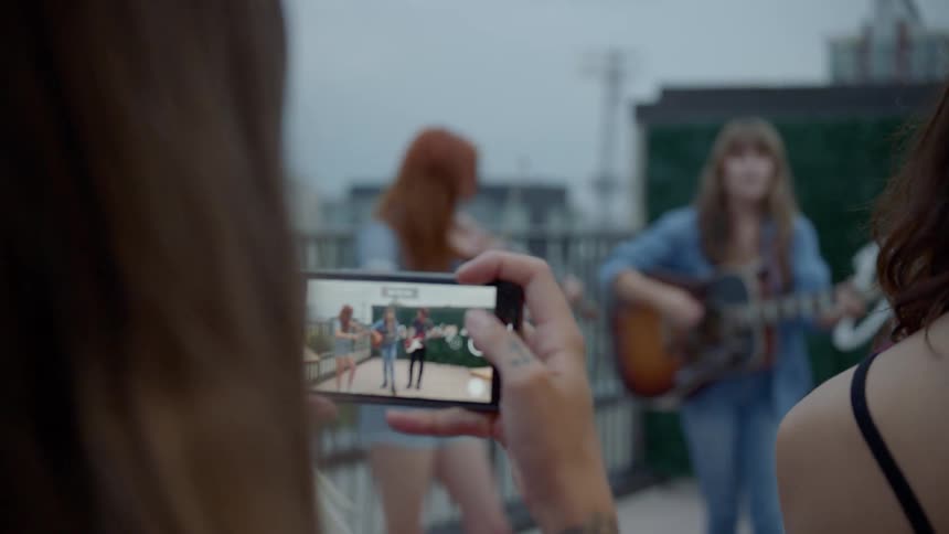 A woman shoots film of a band performing