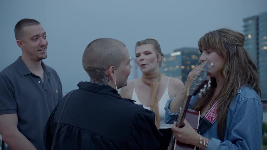 A woman plays her guitar as she stands with her friends