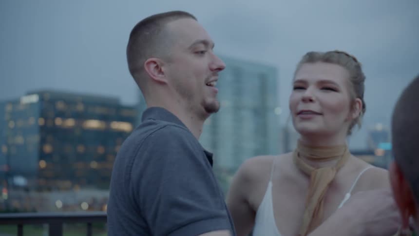 A man and a woman hug with a city in the background