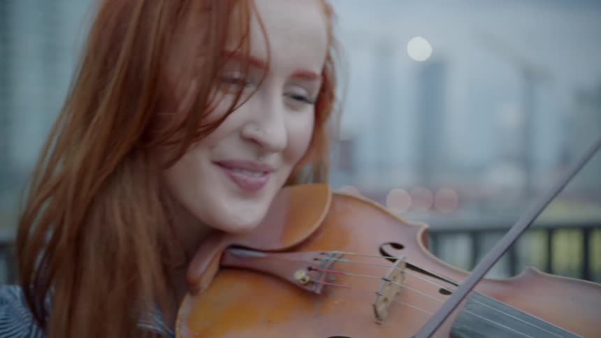 A woman smiles as she plays a violin