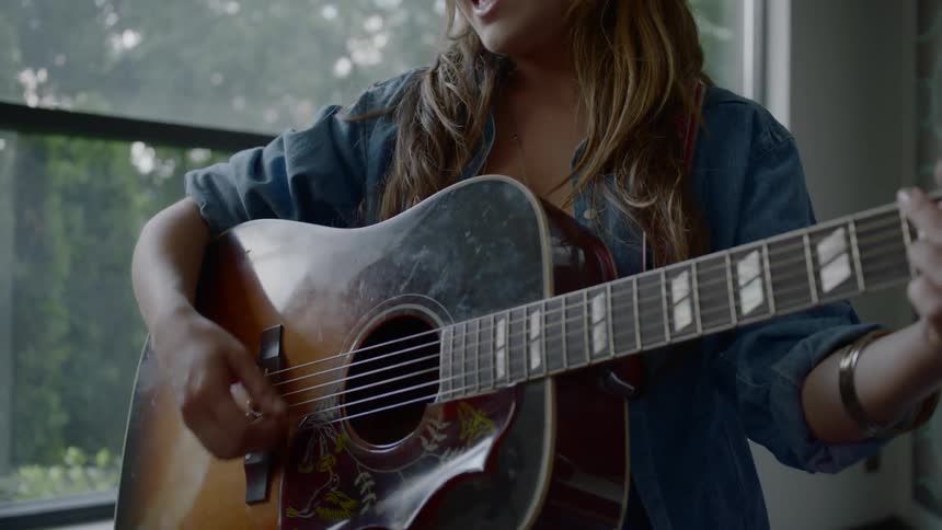 A woman sings and plays the guitar