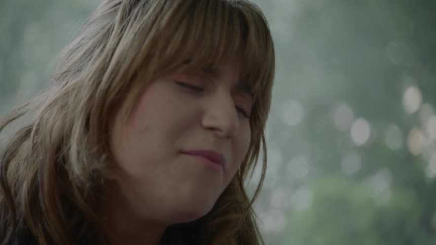 A woman sings in front of a window