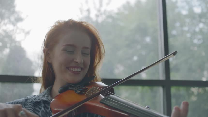 A young redheaded female bows a violin