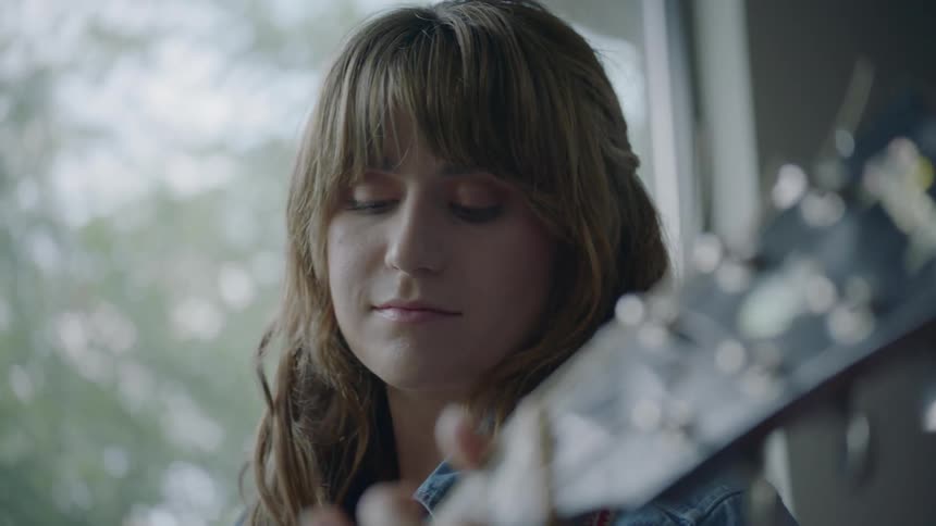 A woman strums a gibson acoustic guitar