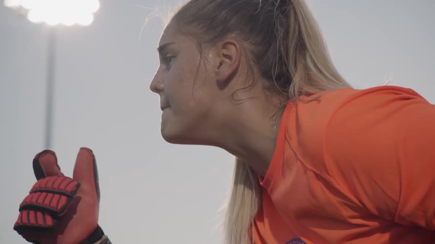 A female soccer goalkeeper gesturing and calling out to teammates
