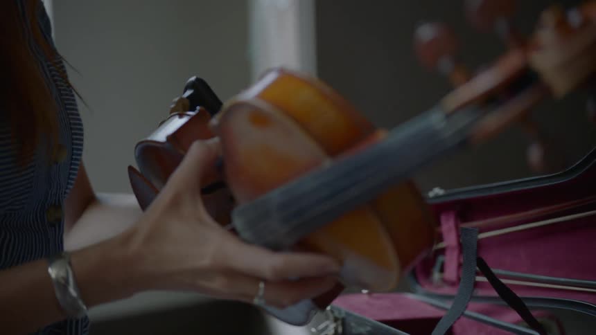 A woman puts a base on the bottom of a violin