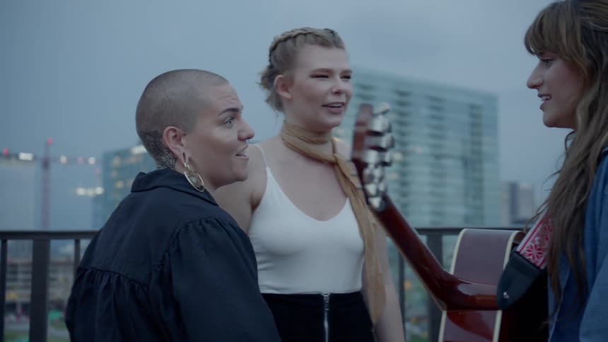 People greeting a musician with a guitar outdoors in the evening