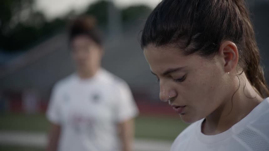 A female takes a deep breath in preparation to take a free kick in a soccer match