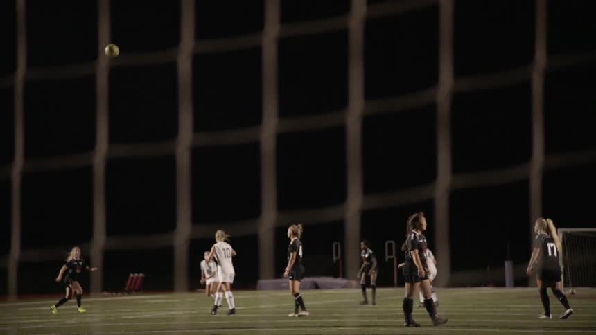 A goalkeeper kicks the ball out in a women's soccer match