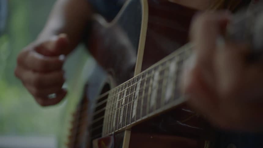 A woman strums an acoustic guitar