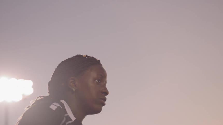 A female soccer player jumps and hits a soccer ball with her head