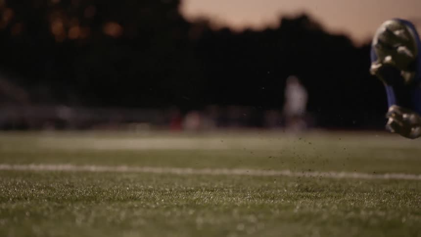 A soccer player kicks the ball at sunset