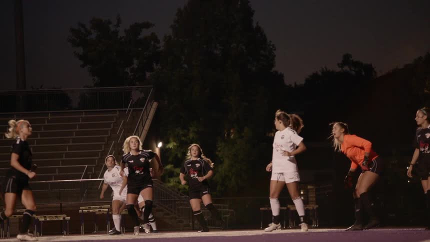 Soccer ball kicked during a game and blonde player head butting the shot
