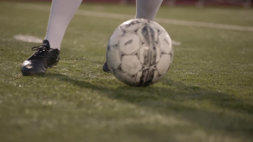 A male on a soccer field kicking a soccer ball