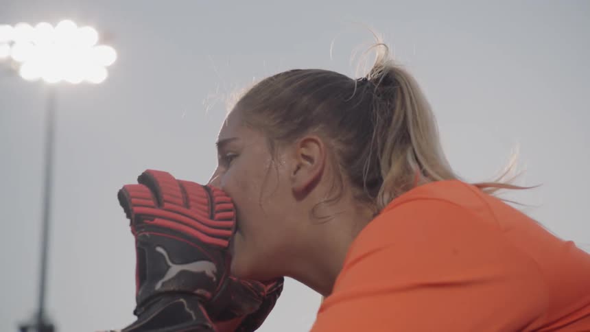 A goalkeeper shouts instructions to her defense in a soccer game