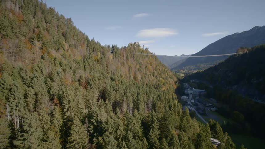 A handful of buildings and roads are tucked deep within a narrow valley within a range of forest covered mountains