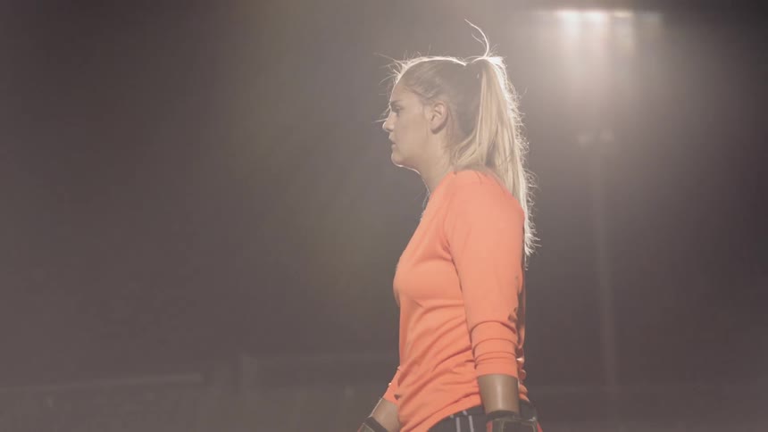 Goalkeeper woman walks on the football field under the stadium lights at night