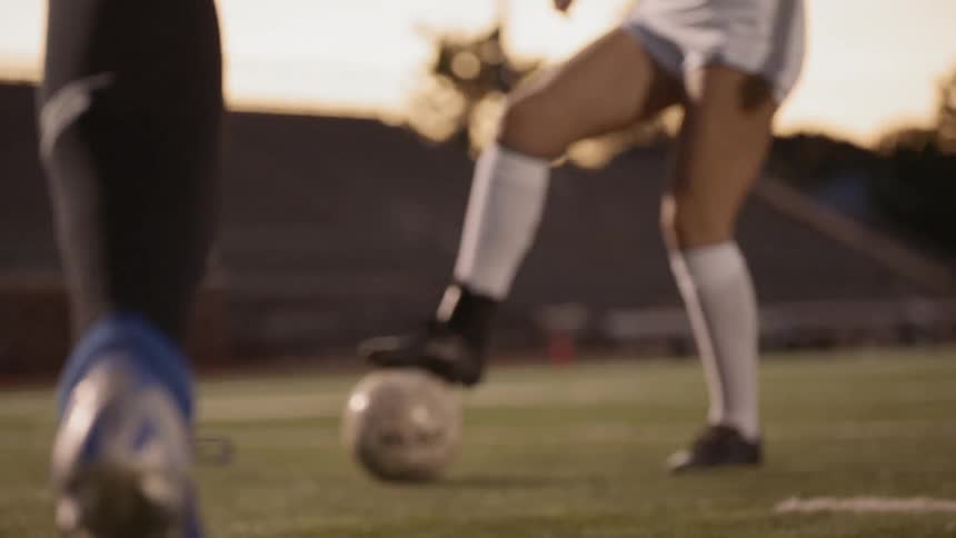 A soccer player dribbles past an opposition defender and passes to a teammate